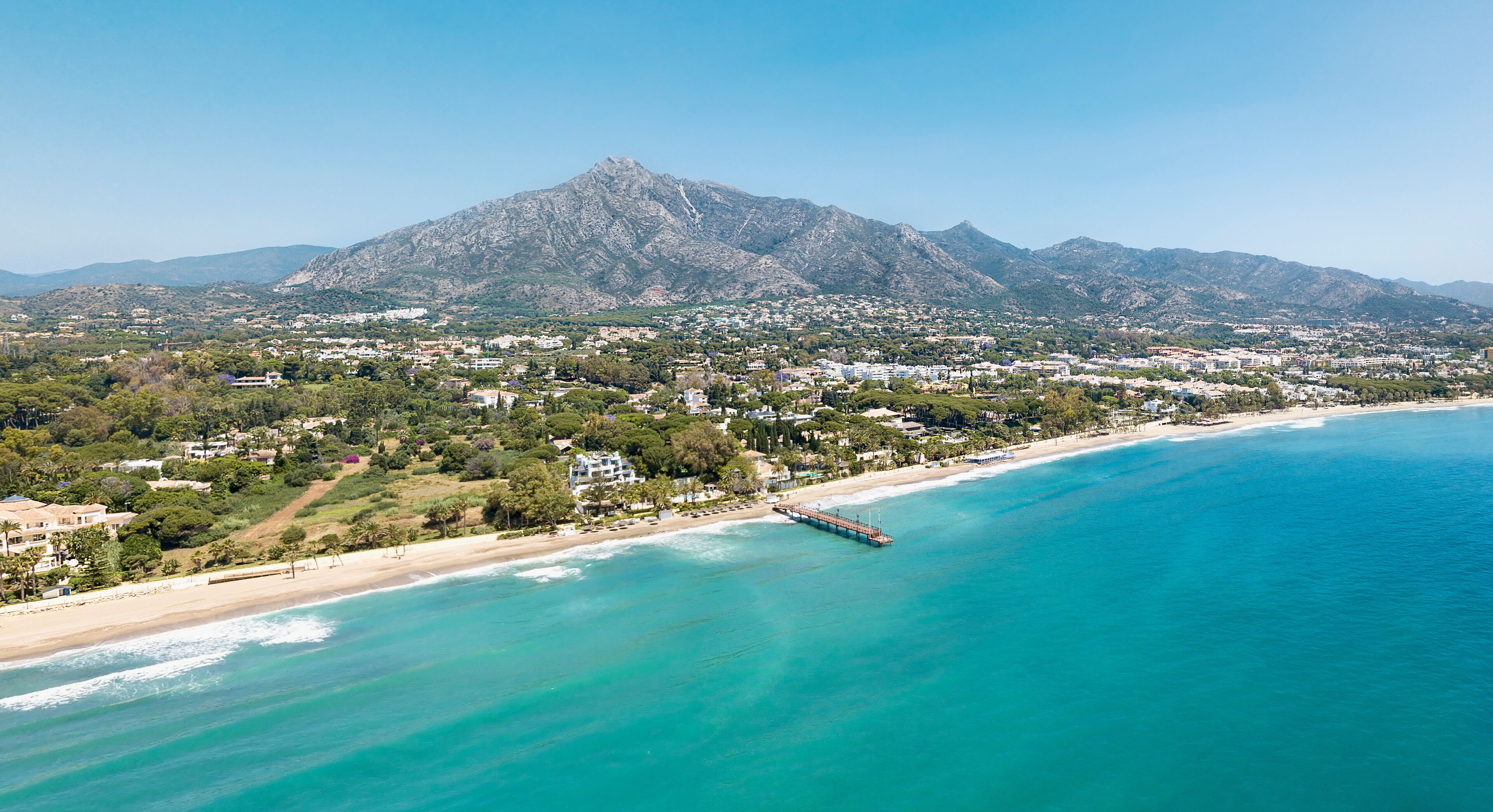 Unique aerial view of luxury and exclusive area in Marbella, golden mile beach, view of Puente Romano Bridge and in background famous La Concha mountain. Emerald water colour 
