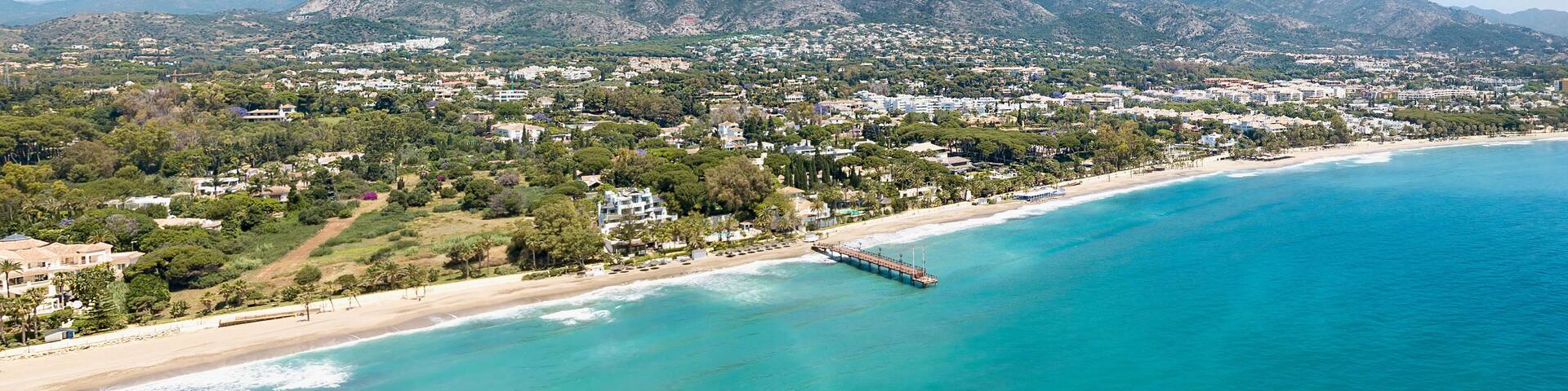 Unique aerial view of luxury and exclusive area in Marbella, golden mile beach, view of Puente Romano Bridge and in background famous La Concha mountain. Emerald water colour