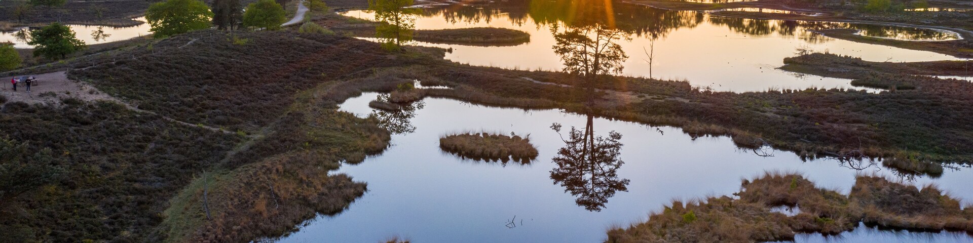 Aerial sunset photo of Hatertse Vennen nature reserve. Located in Heumen, Wijchen, Overasselt, Gelderlands, The Netherlands. The trees reflect in the water
