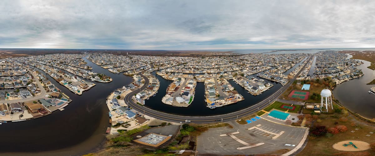 An aerial view of a residential area with a river running through it, surrounded by houses and docks.