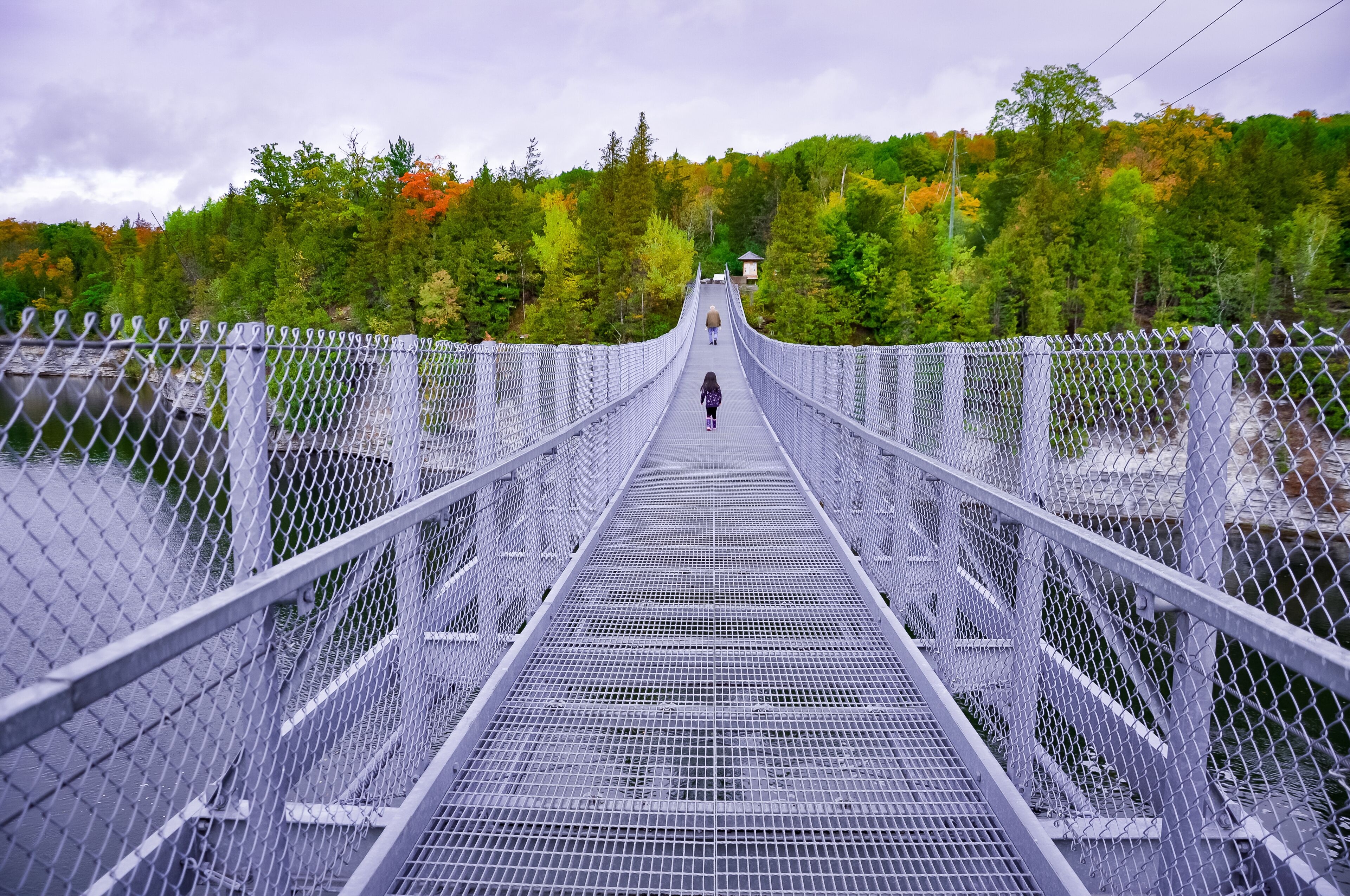 People walking in suspension bridge over the river