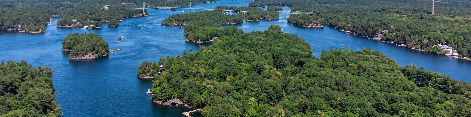 Aerial view of the Saint Lawrence River, Thousand Islands Bridge and 1000 Islands Tower, capturing lush green islands, blue water, and the Canada–US international border on summer day (July 2021)