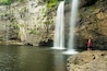 A woman hikiing below waterfall in Fall Creek Falls State Park, Pikeville, Tennesee.