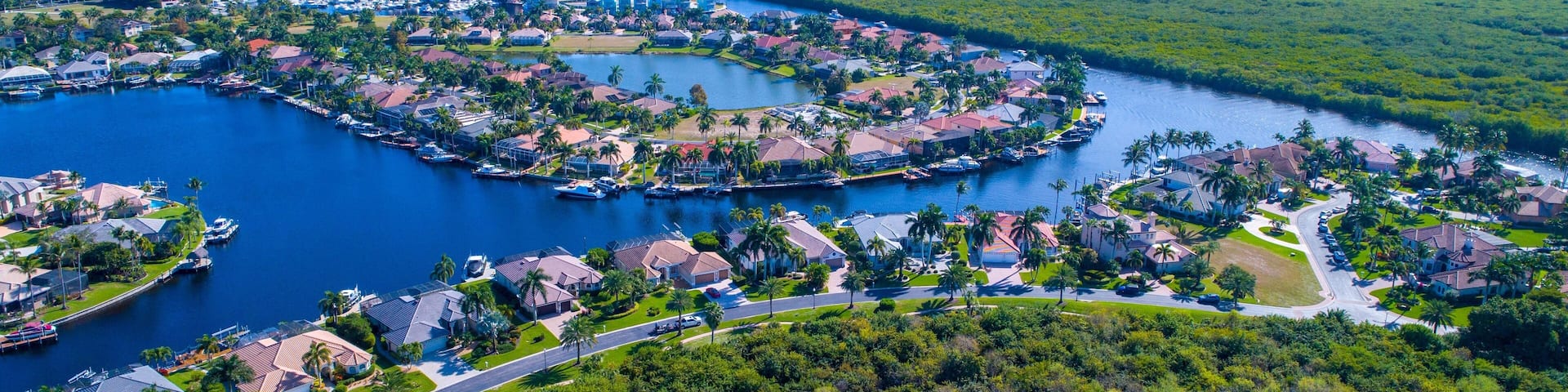 Aerial Drone View of Bay in Cape Coral, Florida with Mangroves and Real Estate in the Foreground and the Caloosahatchee River in the Background