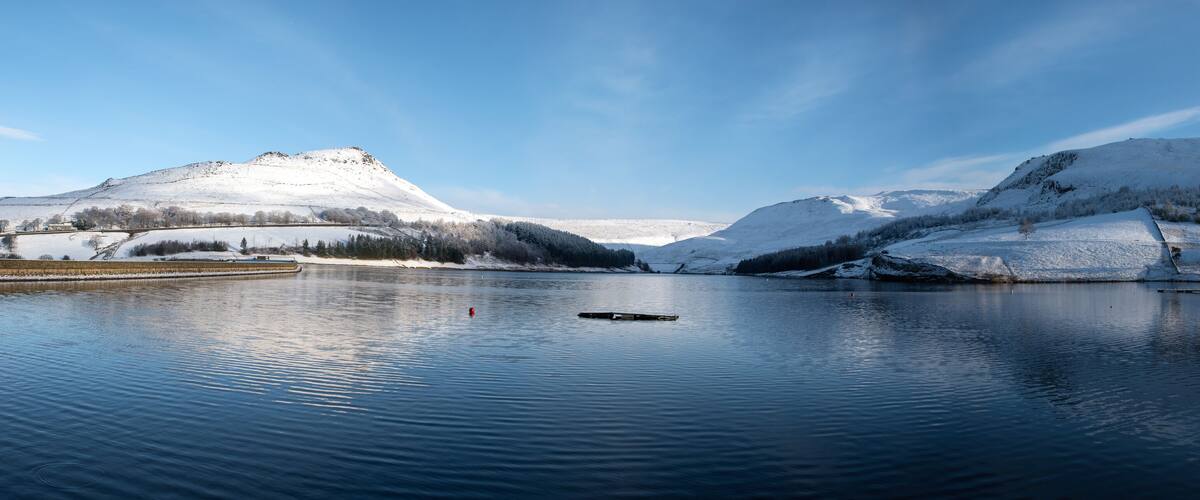 A calm lake surrounded by snow-covered mountains and a clear sky.