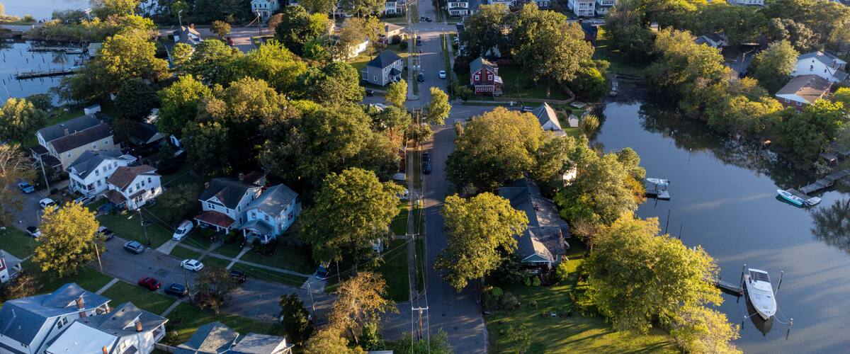 An aerial view of a residential area with houses, trees, and a body of water.