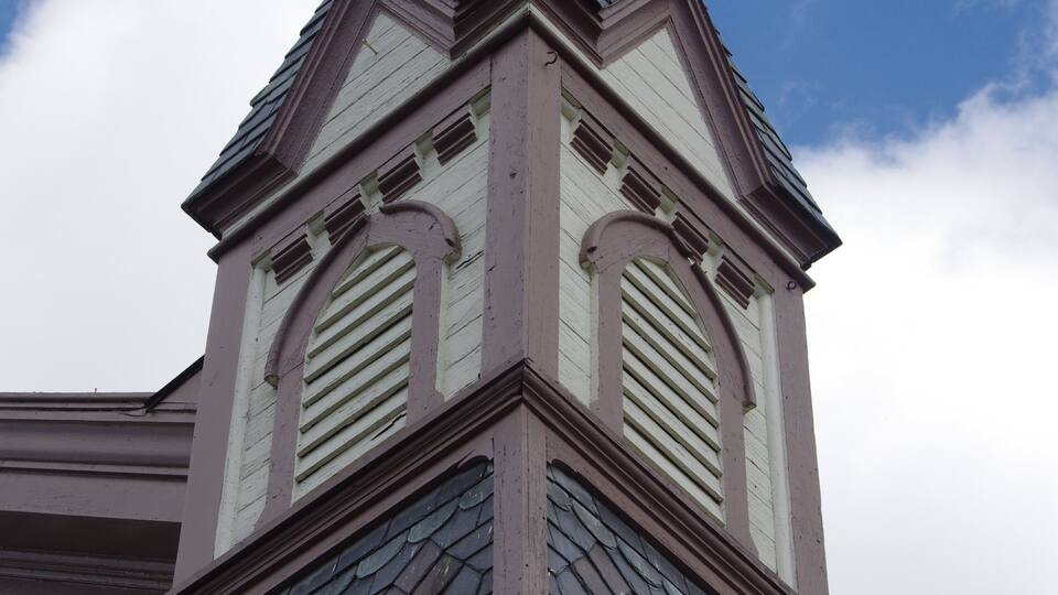 A building with a steeply pitched roof, decorative gables, and a prominent chimney.