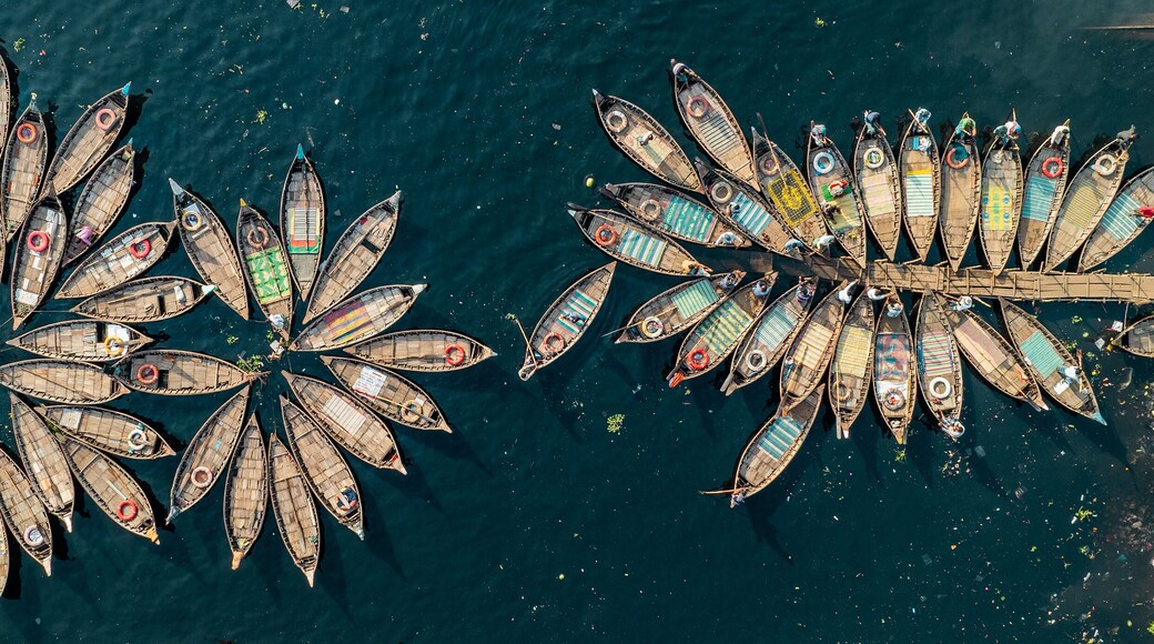 Aerial view of boats clustered together creating a vibrant mosaic on the dark waters, contrasting with the textured shoreline, Dhaka, Dhaka District, Bangladesh.