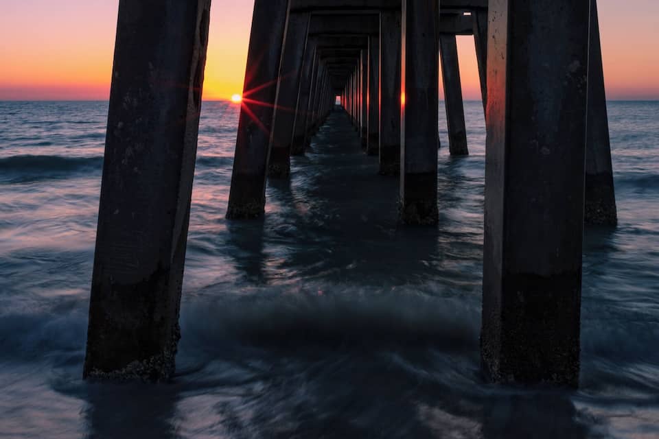 A pier extending into the ocean at sunset.