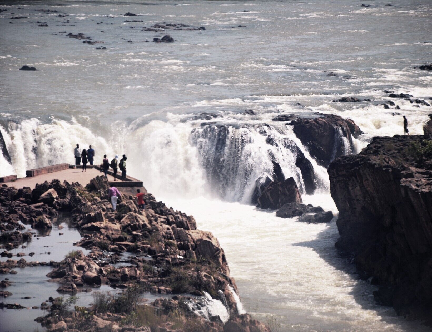 A large waterfall with people observing it.