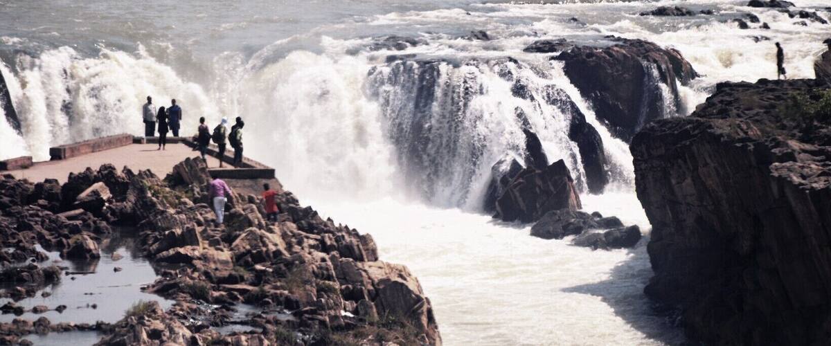 A large waterfall with people observing it.