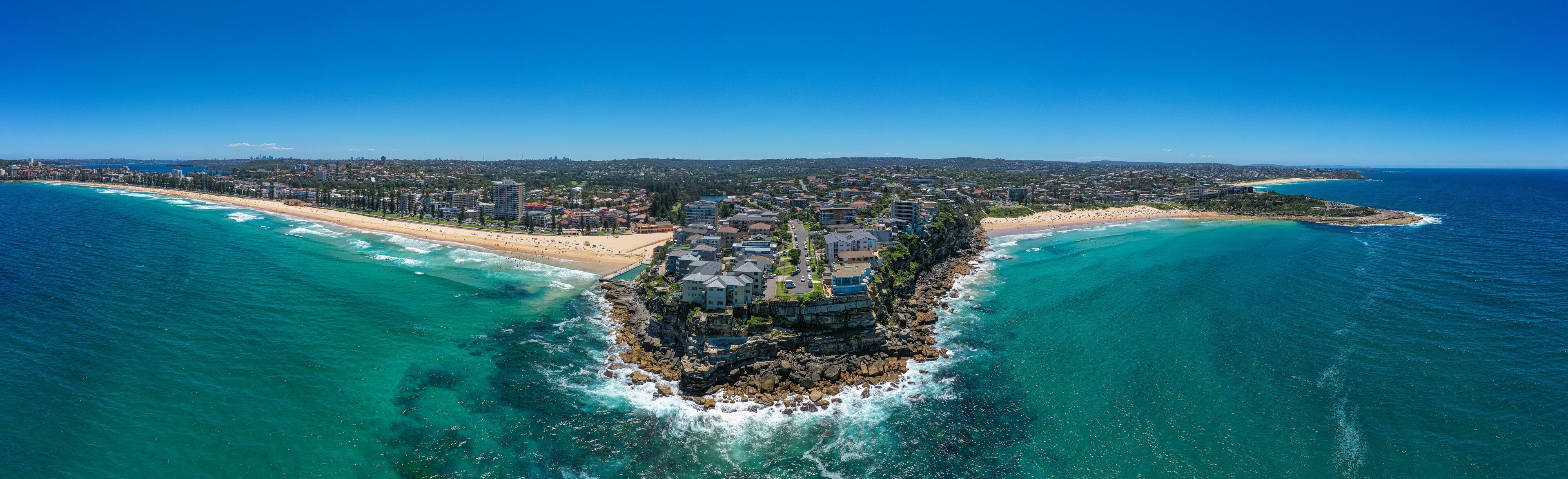 A coastal town with a prominent rocky island surrounded by turquoise waters.
