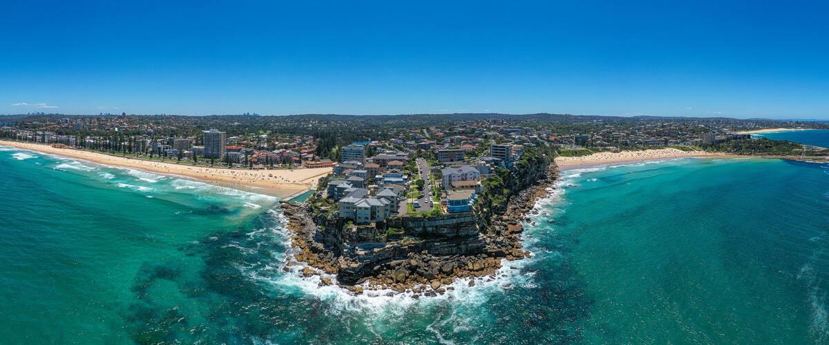 A coastal town with a prominent rocky island surrounded by turquoise waters.