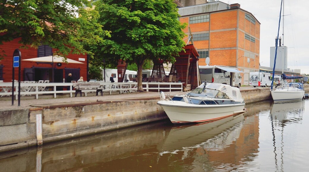 Sailboats moored to a pier near the old industrial building. Enköping, lake Mälaren, Sweden. Summer vacations, travel destinations, tourism, sailing, cruise, recreation, camping, transportation