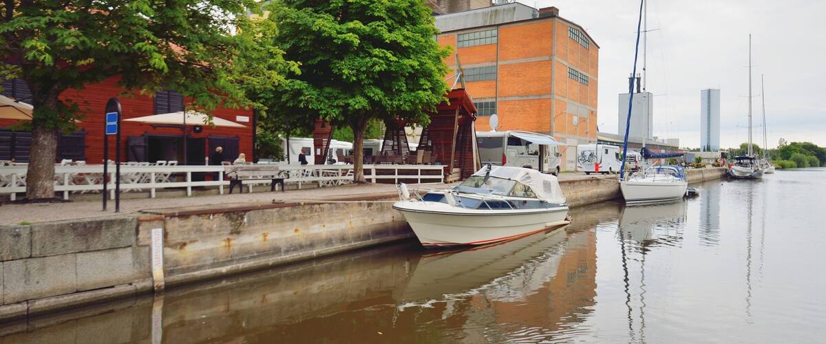 Sailboats moored to a pier near the old industrial building. Enköping, lake Mälaren, Sweden. Summer vacations, travel destinations, tourism, sailing, cruise, recreation, camping, transportation