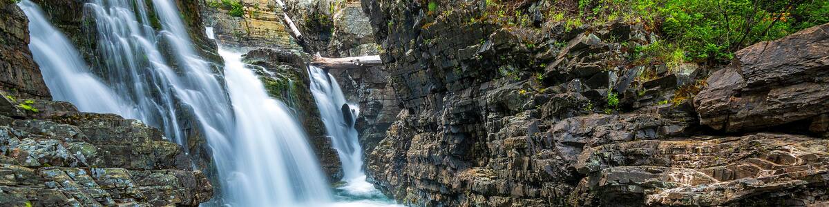 A multi-tiered waterfall cascading over rocky terrain with clear water.