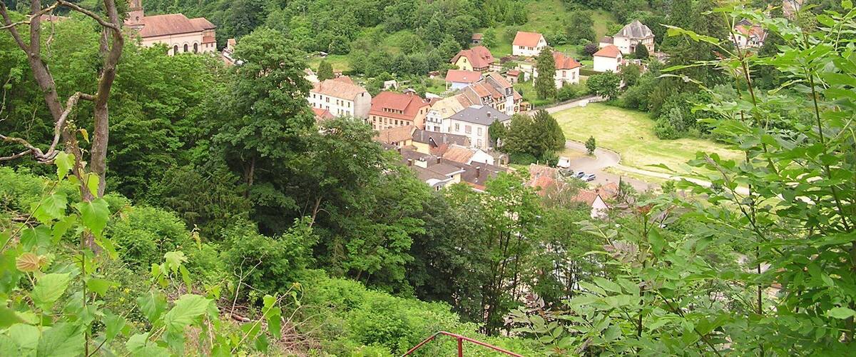 A village nestled in a valley surrounded by rolling hills and dense forests.