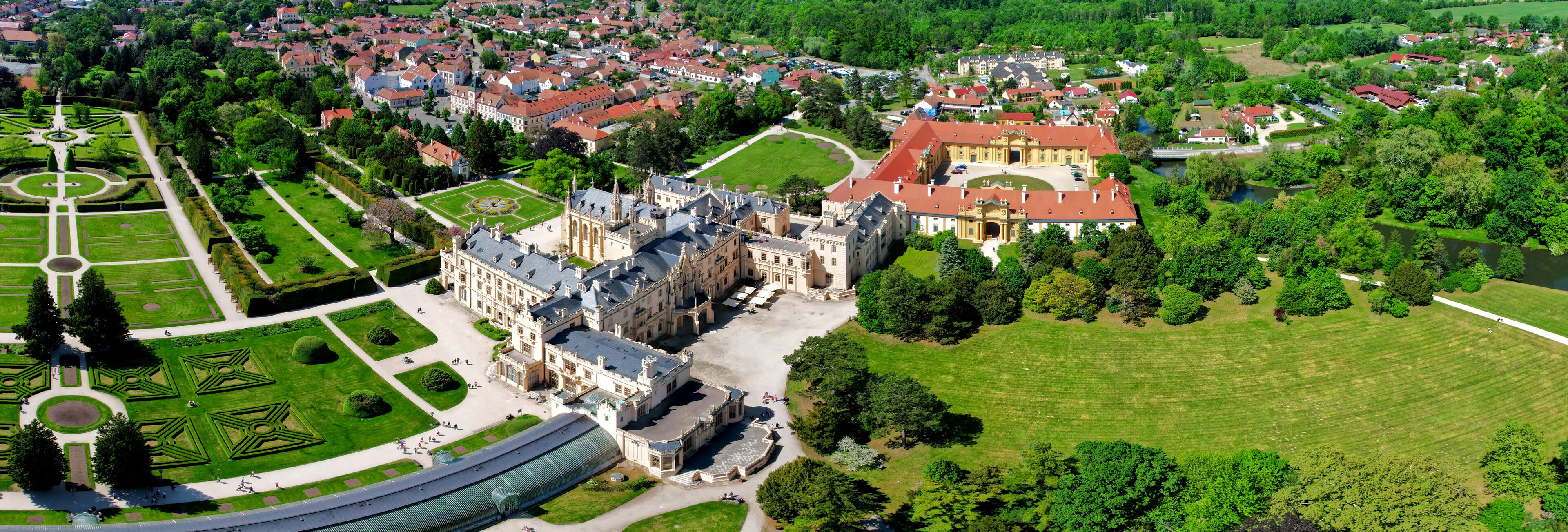 An aerial view of a historic estate with a large central building, formal gardens, and surrounding residential areas.