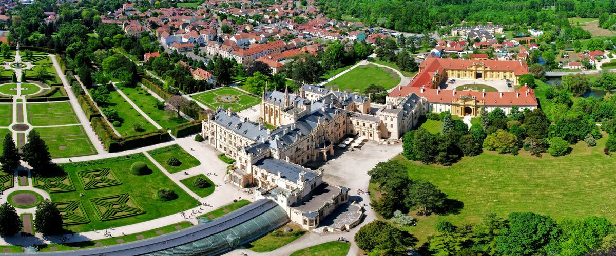 An aerial view of a historic estate with a large central building, formal gardens, and surrounding residential areas.