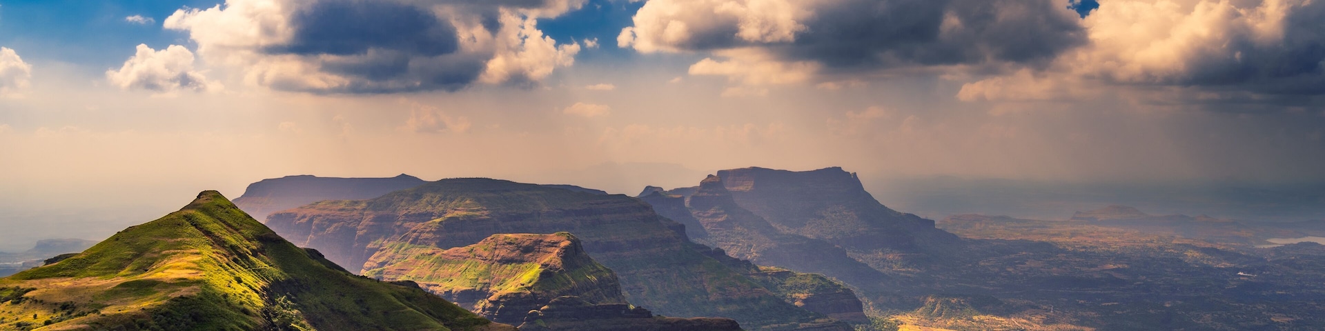 A mountainous landscape with green slopes and a valley.