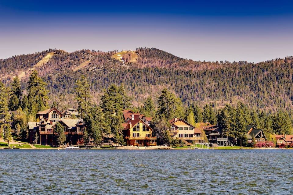 A lakeside community with houses and a mountain backdrop.