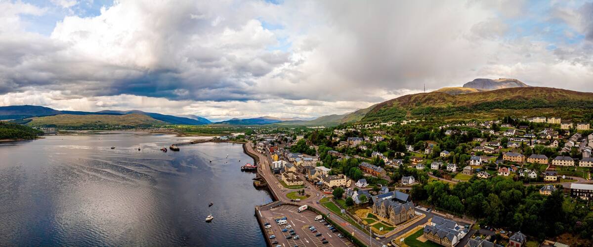 A coastal town with a river, hills, and a large building.