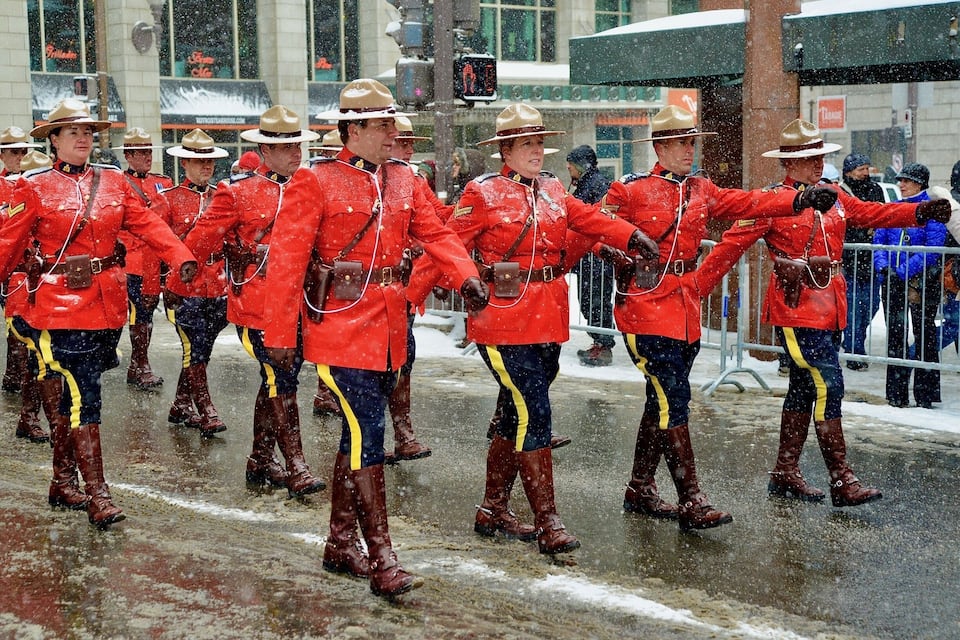Un groupe de personnes vêtues d’uniformes rouges défile sous la pluie.