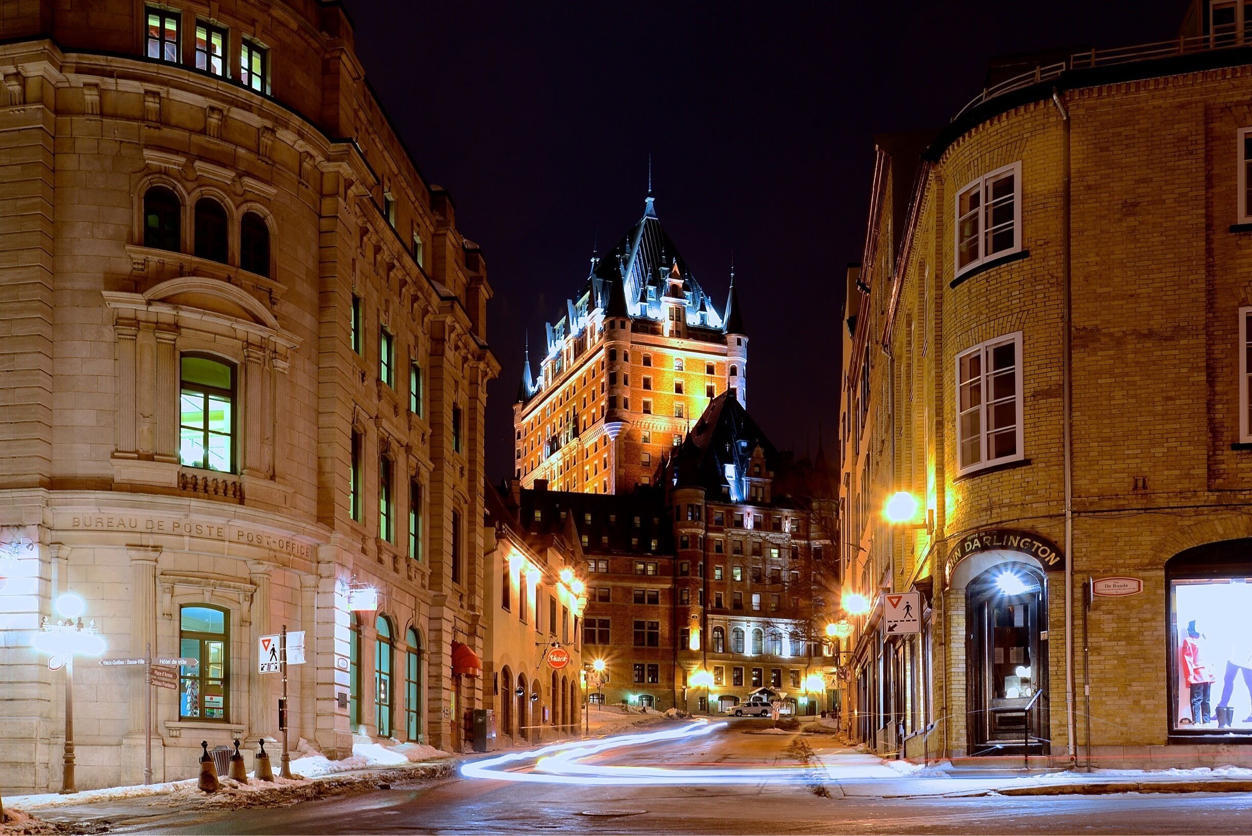 A snow-covered street with historic buildings and a prominent tower in the background.