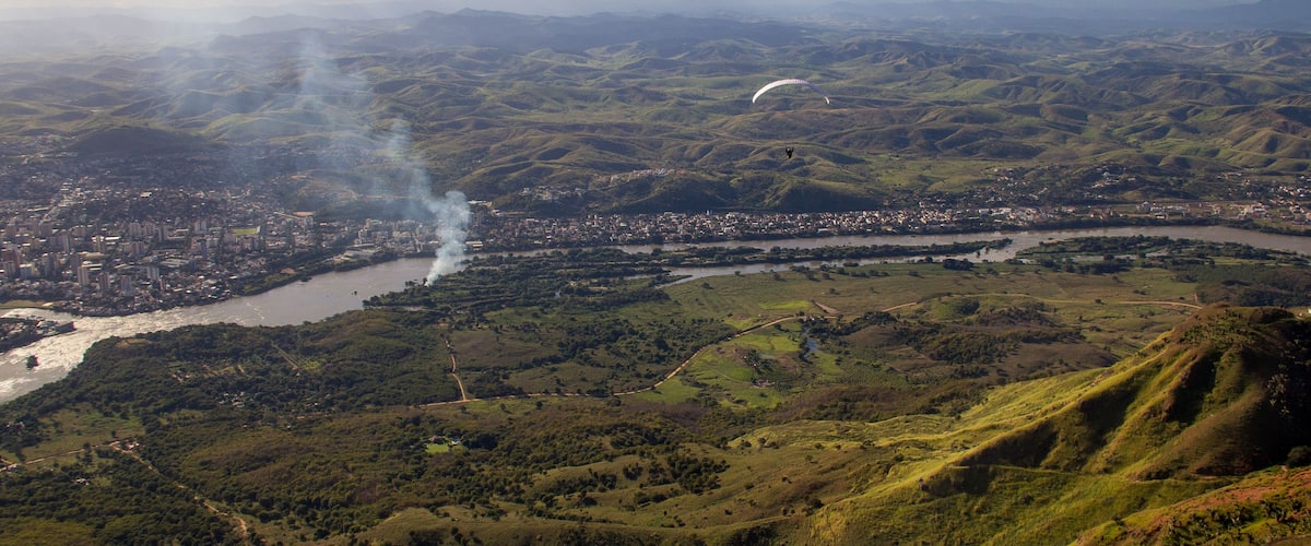 A river winding through a valley with a city on one side and hills on the other.