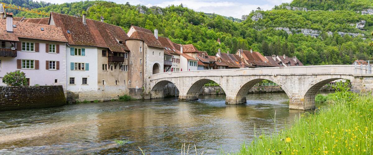 Cityscape with bridge crossing river Doubs in picturesque village Saint-Ursanne in canton Jura destrict Porrentruy in Switserland