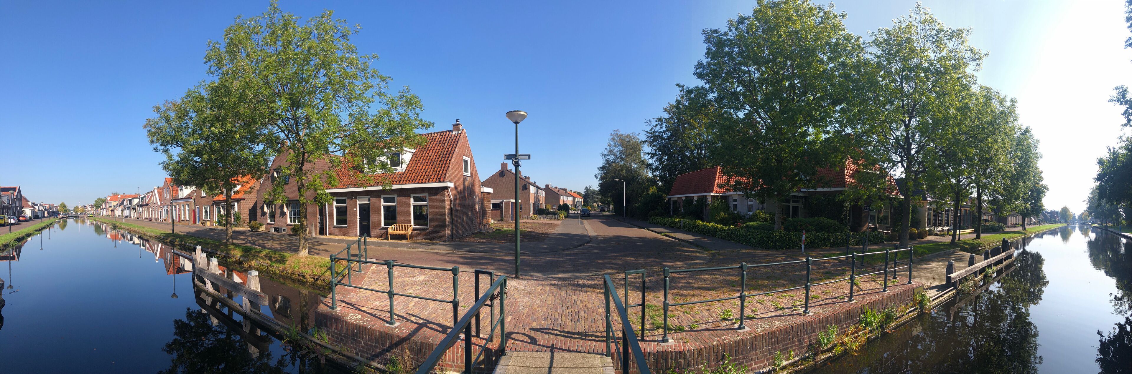 A canal with houses on one side and trees on the other.