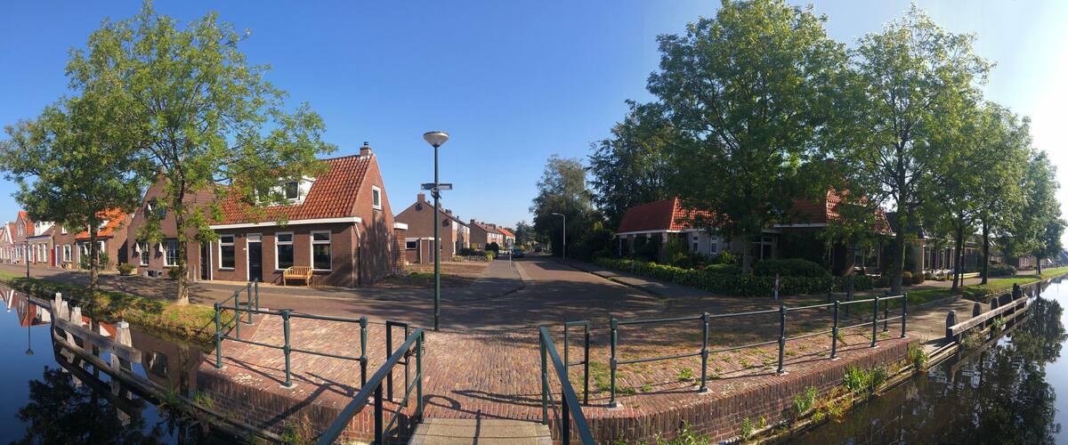 A canal with houses on one side and trees on the other.