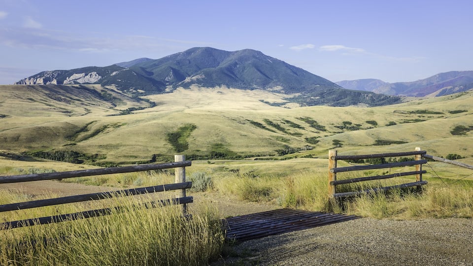 A mountain landscape with a wooden fence in the foreground.