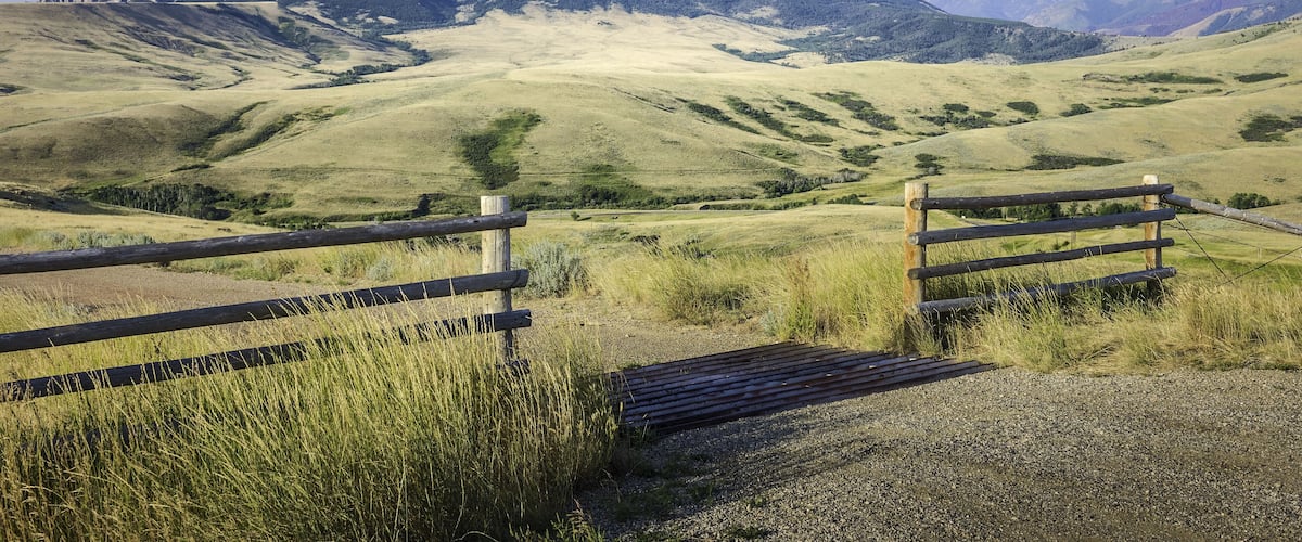 A mountain landscape with a wooden fence in the foreground.