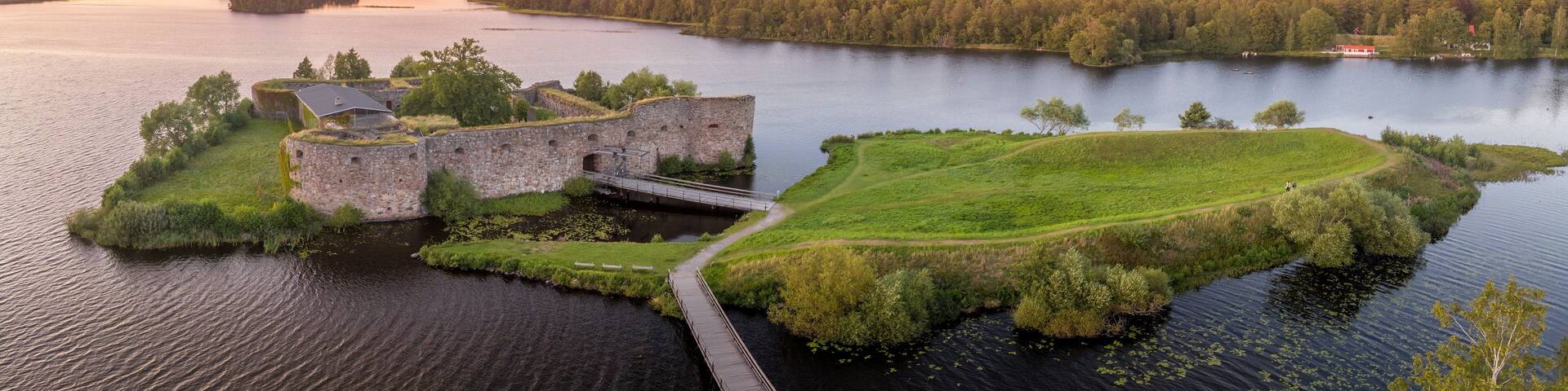 Aerial view of Kronoberg castle ruin on Helgasjön lake in Växjö Municipality in southern Småland, with dramatic sunset sky