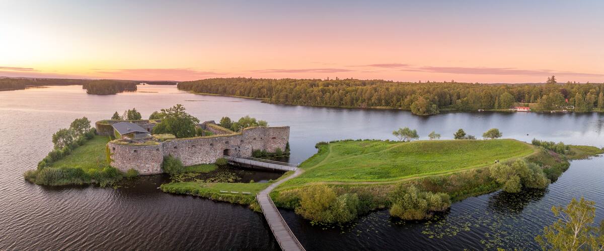 A historic fort on a grassy island surrounded by water, with a bridge connecting it to the mainland.