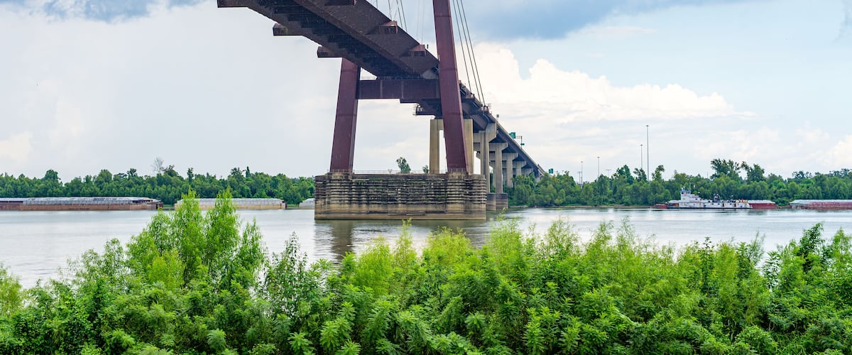 Wide View of the Hale Boggs Bridge over the Mississippi River with Tugboat and Barges Blurred in the Background