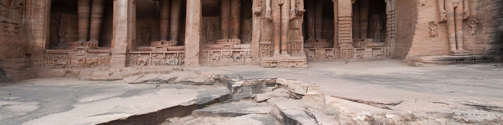 A rock-cut temple with multiple statues and intricate carvings.