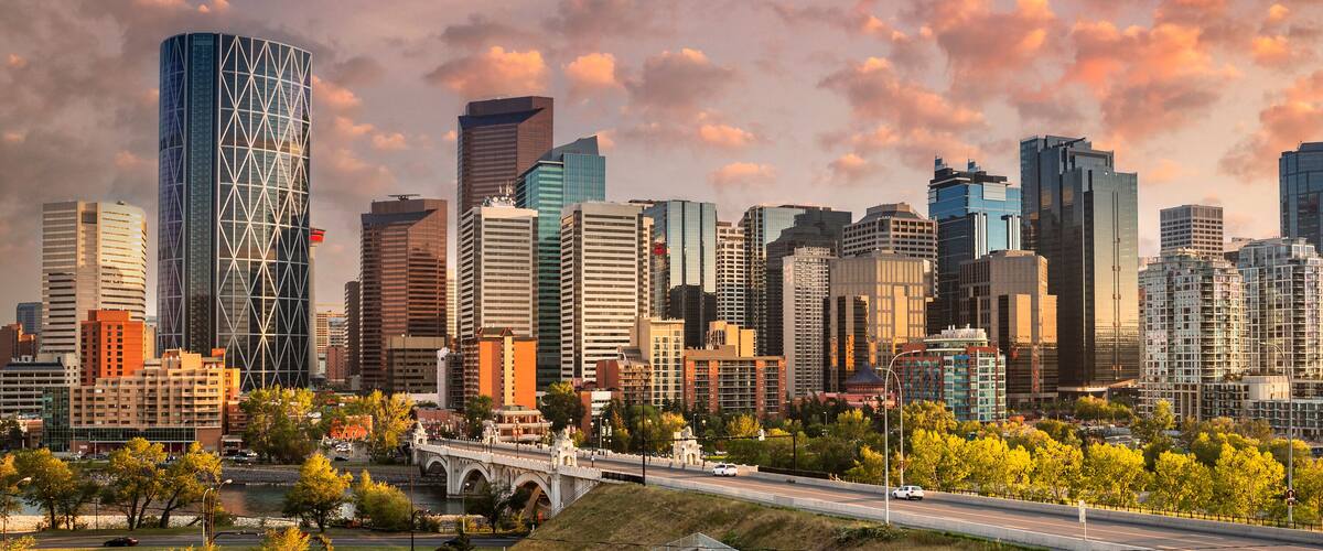 A city skyline with modern skyscrapers and a river in the foreground.