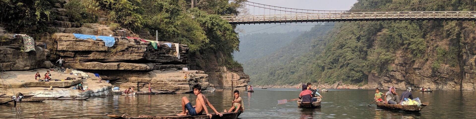 A river with boats, a bridge, and rocky cliffs.