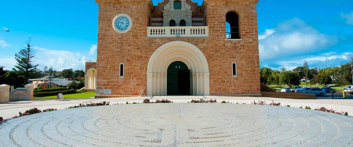 A large brick church with two bell towers and a circular driveway in front.