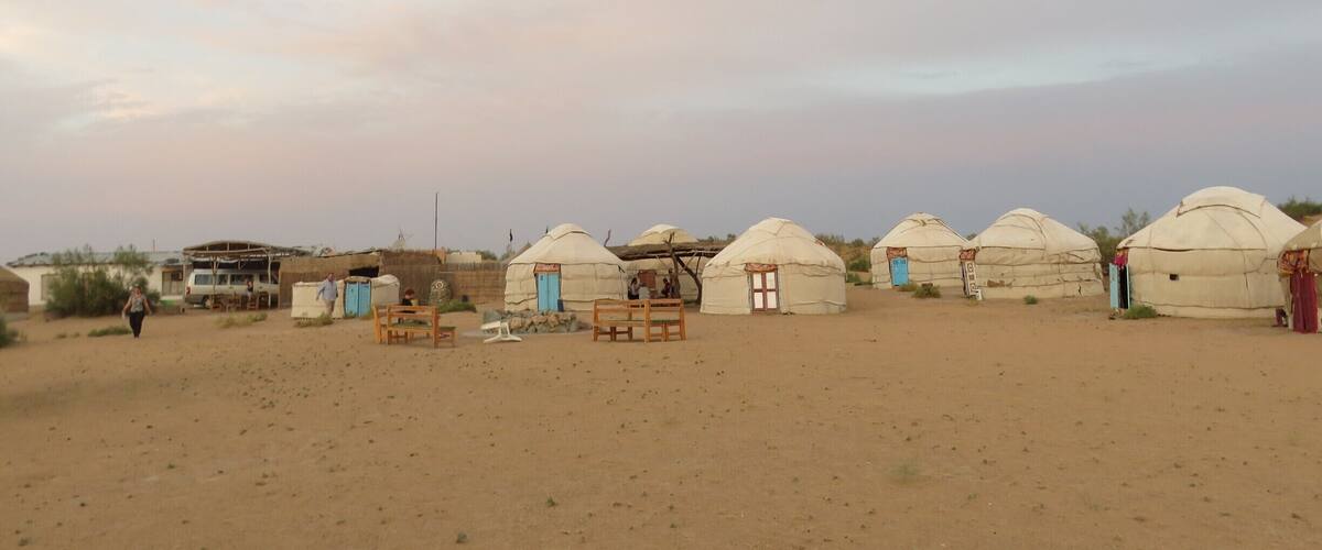 Yurts in a desert landscape with sparse vegetation and a clear sky.