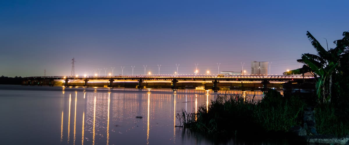A bridge at dusk with lights reflecting on the water.
