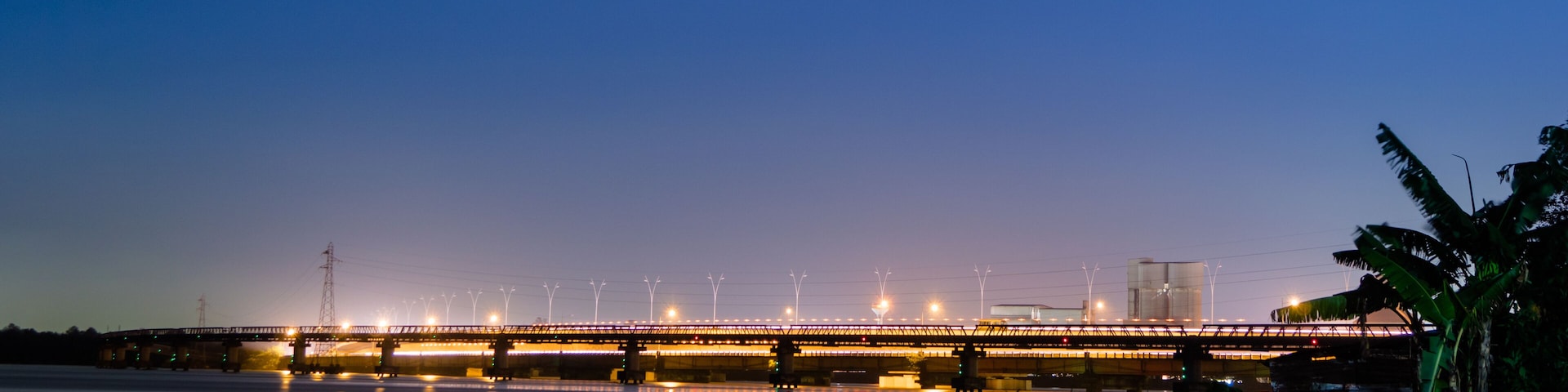 A bridge at dusk with lights reflecting on the water.