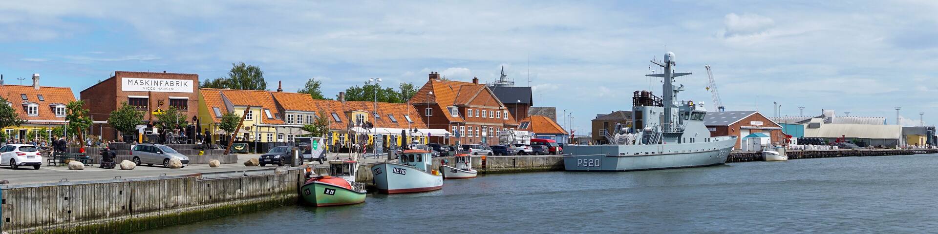 A harbor with boats, a large ship, and buildings along the waterfront.