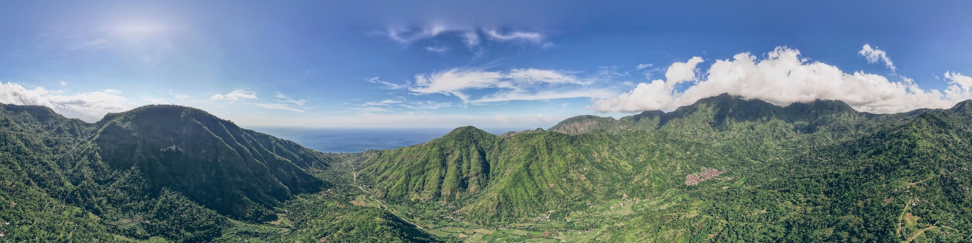 Panoramic overview of Mount Abang and surrounding mountains, with a blue sky, lush vegetation and an ocean view; Abang, Kabupaten Karangasem, Bangli Regency, Bali, Indonesia