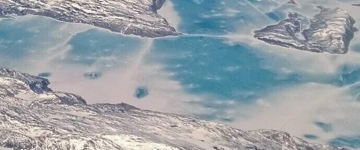 A glacier with icebergs in a blue body of water.