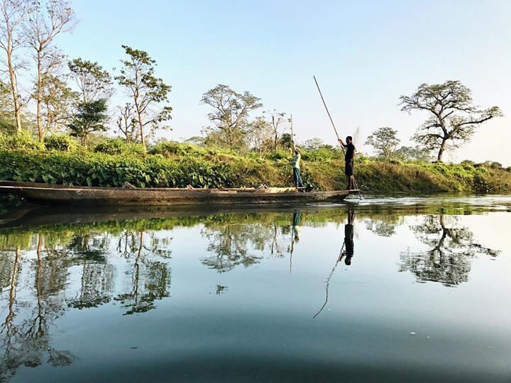 Um rio calmo com pessoas em um barco, cercado por árvores e vegetação.