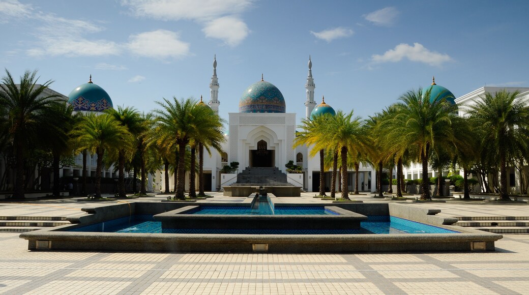 A mosque with two large domes, a minaret, and a fountain in the foreground.