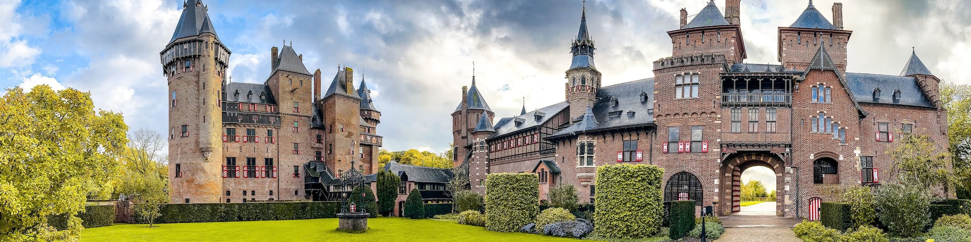 A large, historic brick castle with multiple towers and a well-maintained garden.